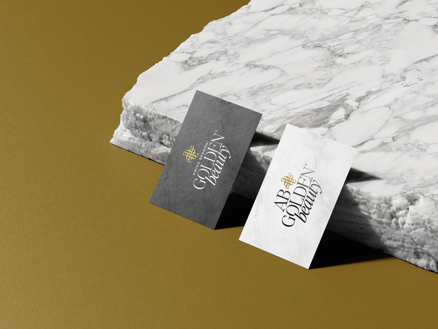 I biglietti da visita AB Golden Beauty, uno nero e uno bianco, sul marmo