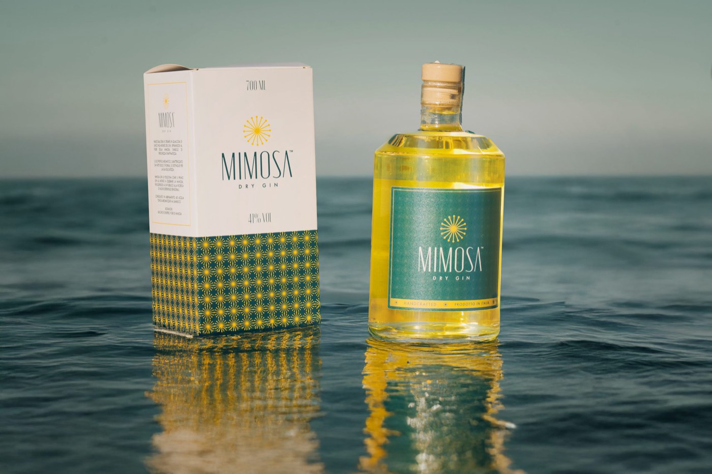 La bottiglia di gin Mimosa e il suo astuccio in riva al mare