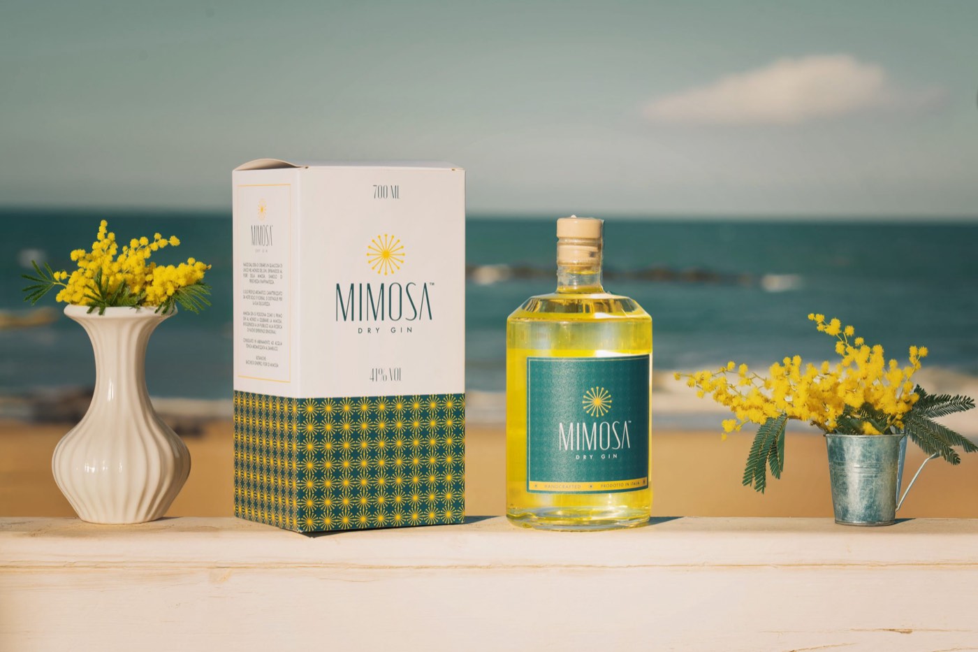 Bottiglia e astuccio Mimosa accanto a un vaso di fiori di mimosa